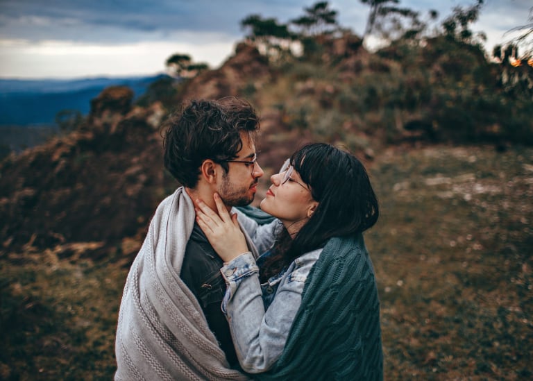 Couple about to kiss, wrapped in a blanket, symbolizing the importance of sexology in relational well-being