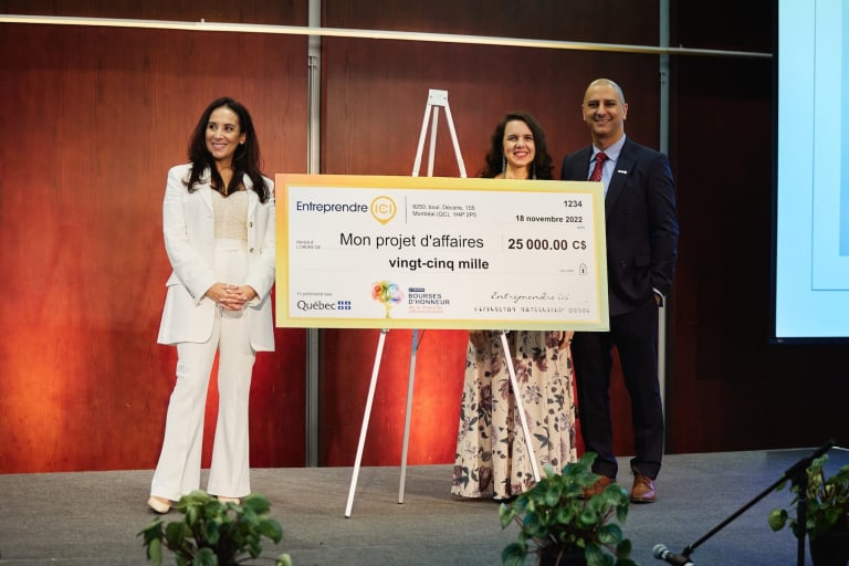 Founder of Divan Bleu accepting a check for $25,000, illustrating the success and financial support received through the grant