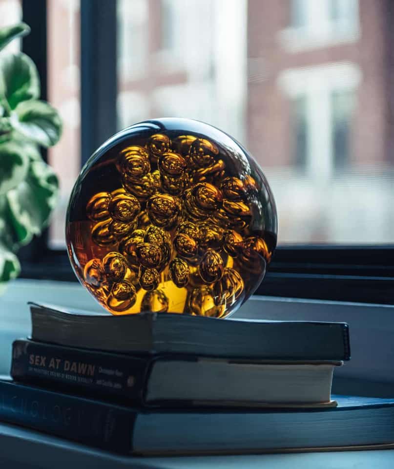 une œuvre d'art en verre sphérique assise sur une pile de livres de psychologie