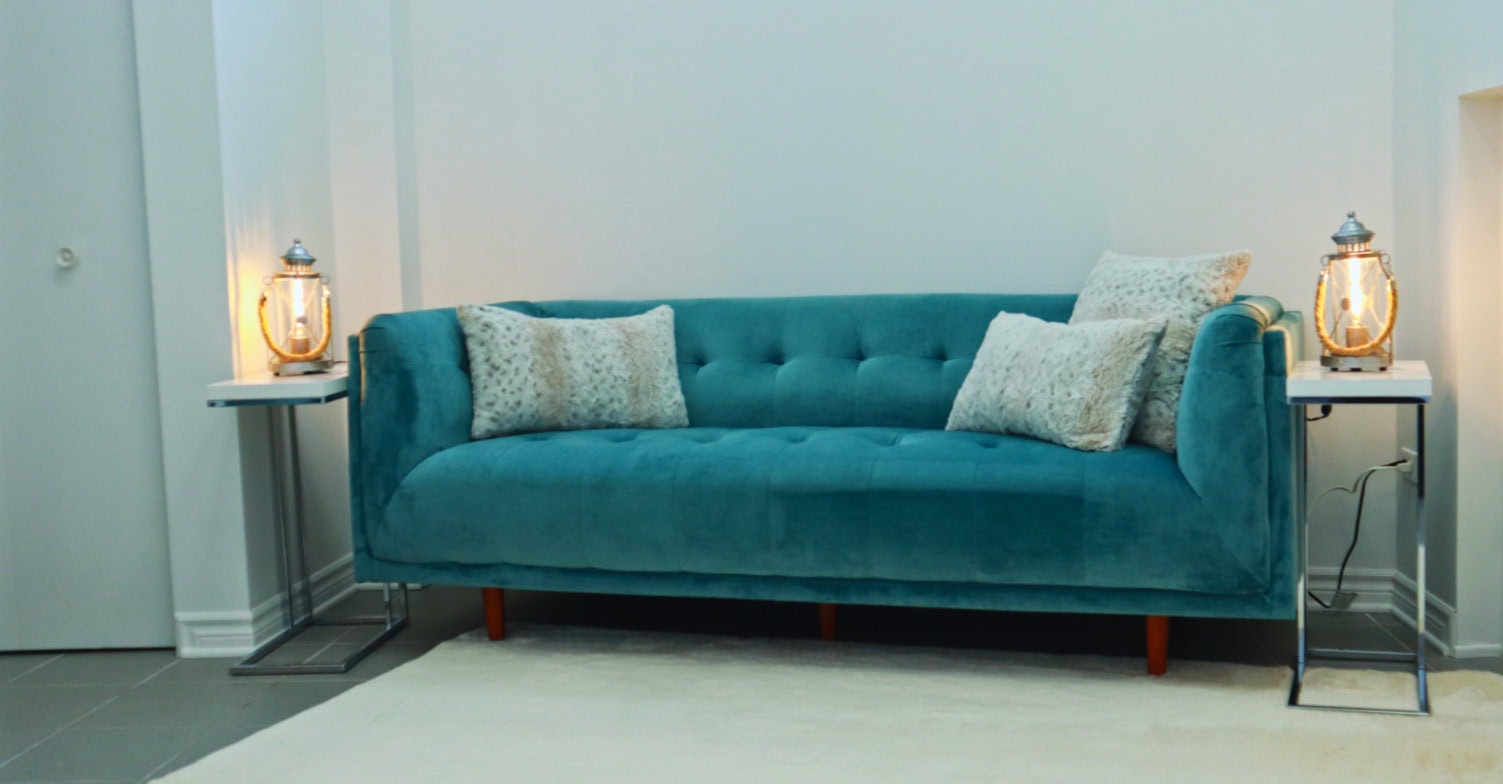 Un canapé turquoise avec ses tables d'appoint et un tapis blanc en peluche.