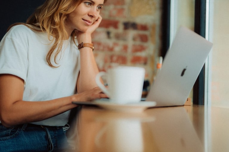 Woman on a laptop with a cup of tea next to it, illustrating preparation for online therapy