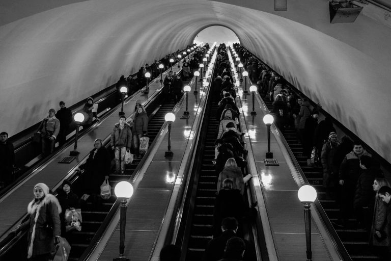 une photo en noir et blanc de 4 escaliers mécaniques avec beaucoup de monde dessus