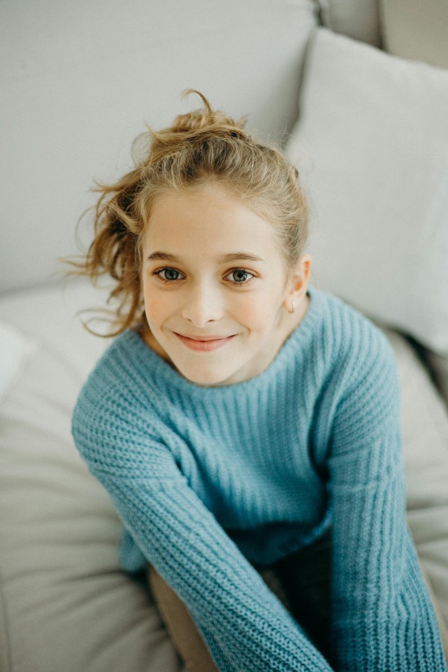 A young girl wearing a blue sweater illustrating the service for adolescent therapy.