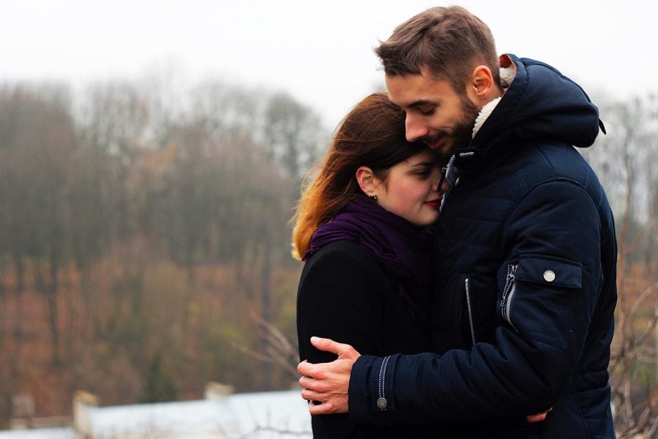 Couple qui s’enlace, un sourire de satisfaction sur le visage
